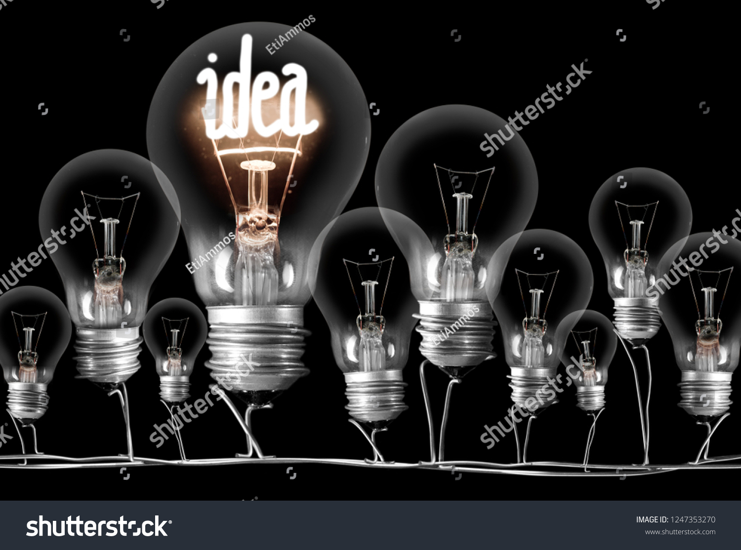 Photo of dark and shining light bulbs with fibe in IDEA shape; concept of idea, innovation, uniqueness and standing out; isolated on black background #1247353270