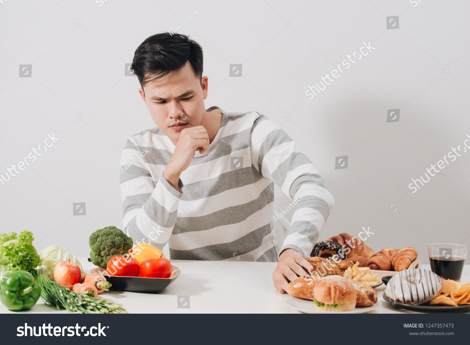 Man having hard choice between healthy and unhealthy food #1247357473