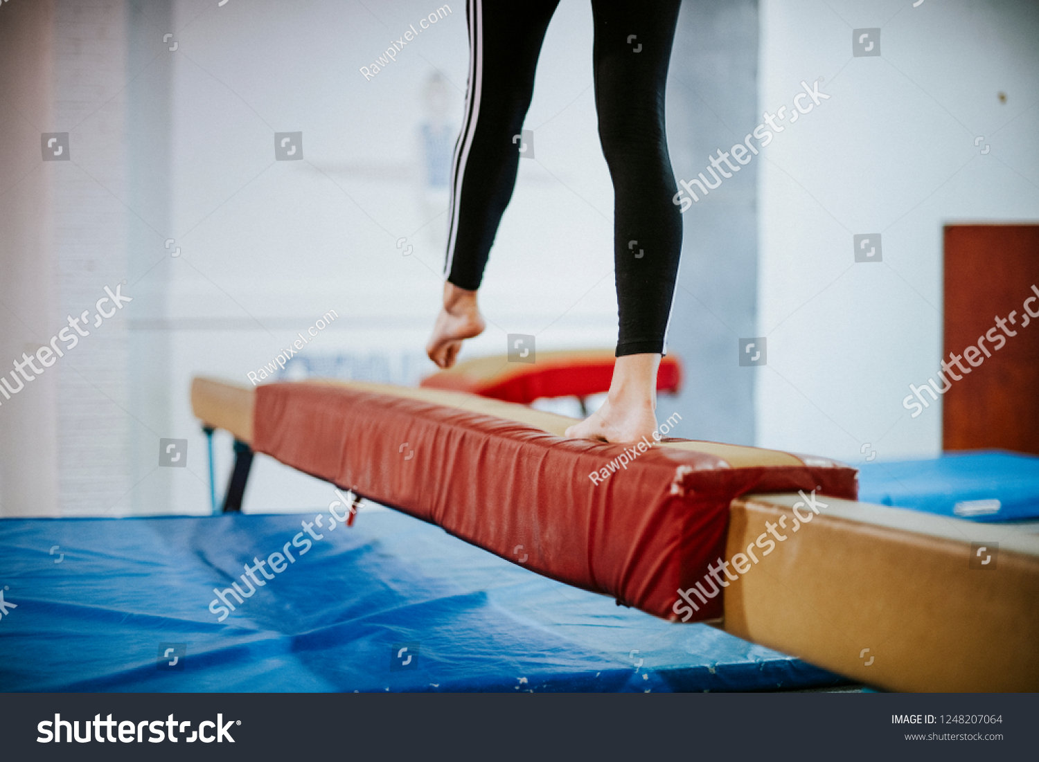 Young gymnast balancing on a balance beam #1248207064