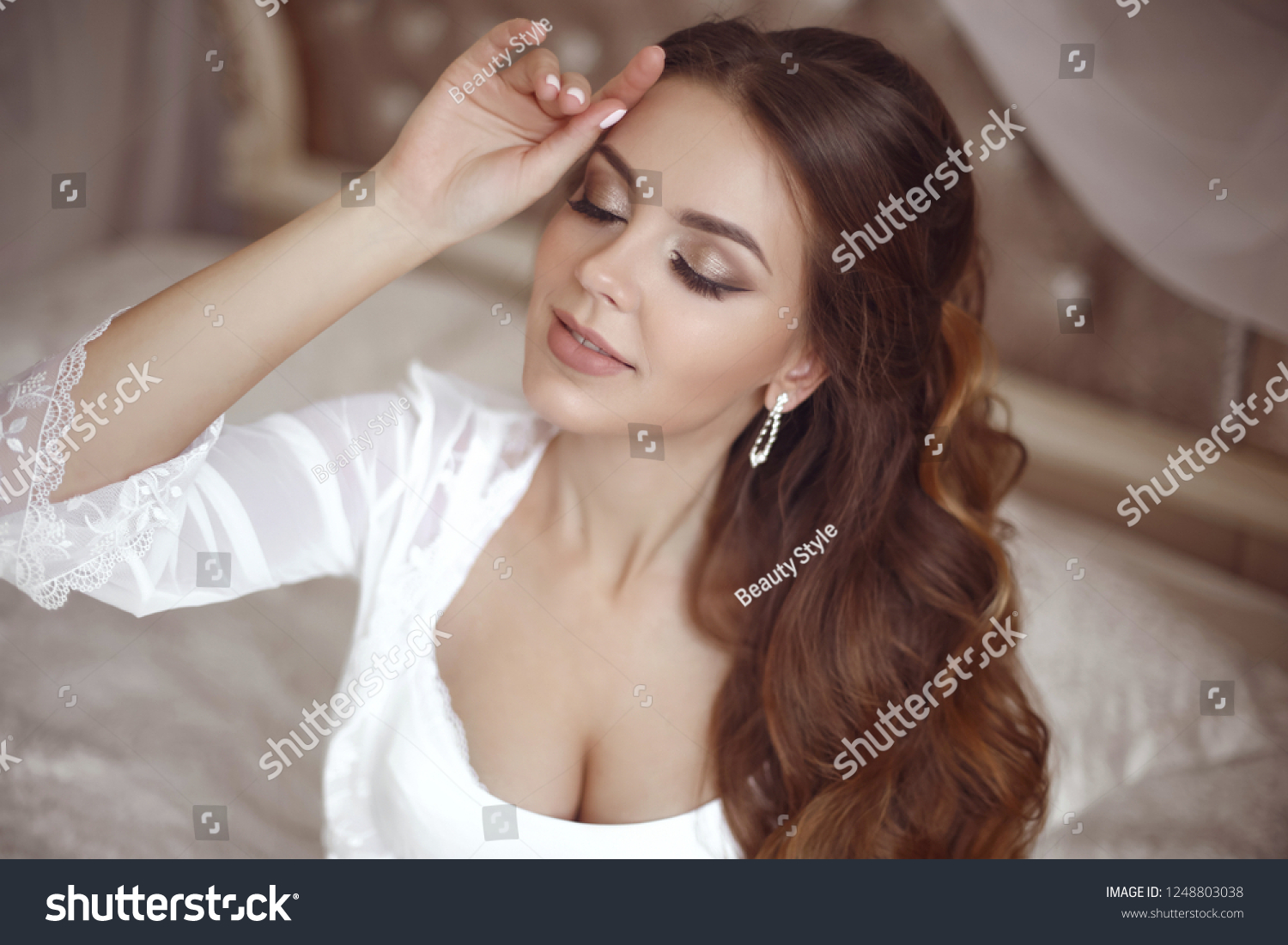 Beautiful sensual Bride wedding Portrait. Beauty makeup and elegant hairstyle. Brunette with curly hair style wearing in white sexy boudoir dressing gown in bedroom. Eyeshadows closeup. #1248803038