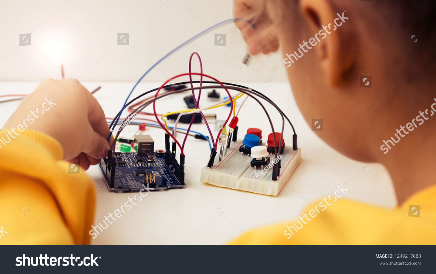 A cute girl constructs robot arduino and program it. The boards and microcontrollers are on the table. STEM education inscription. Programming. Mathematics. The science. Technologie. DIY.  #1249217683