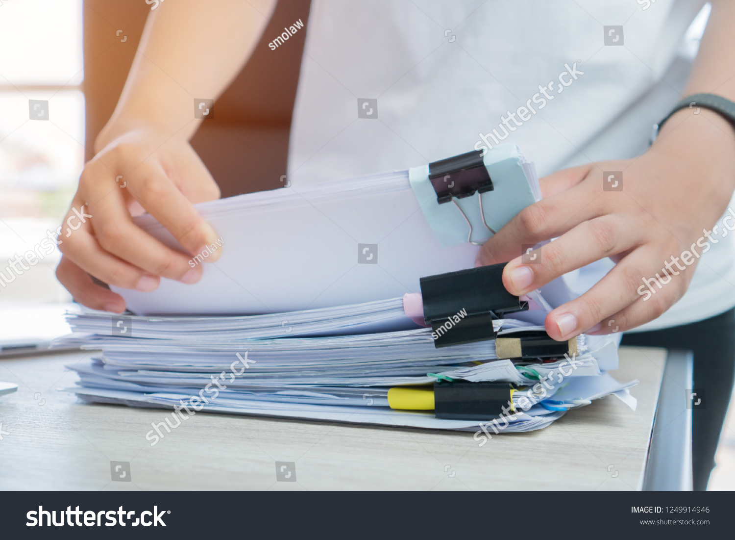 Business Documents concept : Businessman hands working in Stacks paper files for searching and checking unfinished document achieves with clip papers on busy work desk office. Soft focus #1249914946