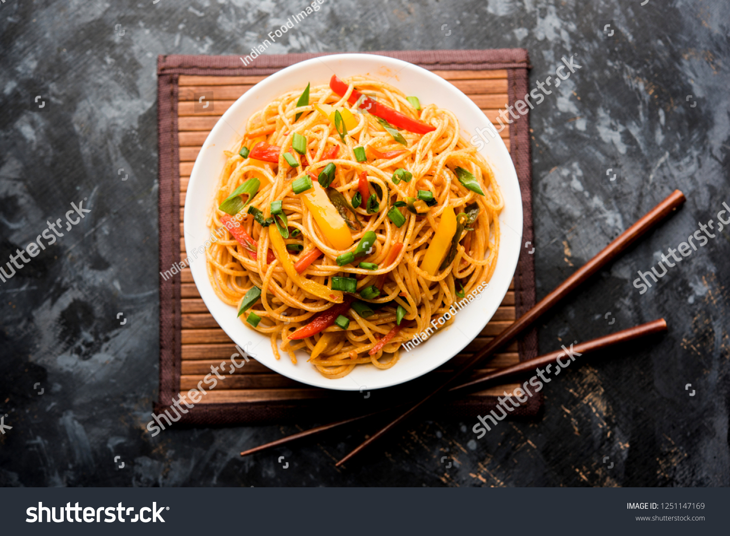 Schezwan Noodles or vegetable Hakka Noodles or chow mein is a popular Indo-Chinese recipes, served in a bowl or plate with wooden chopsticks. selective focus #1251147169