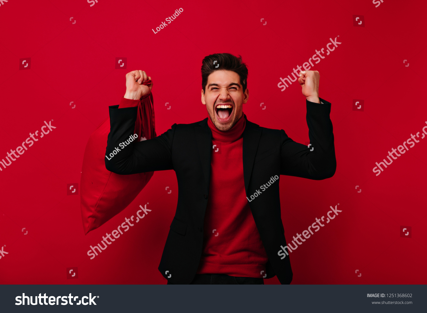 Joyful man with trendy haircut expressing happiness on red background. Refined caucasian guy posing in black jacket. #1251368602