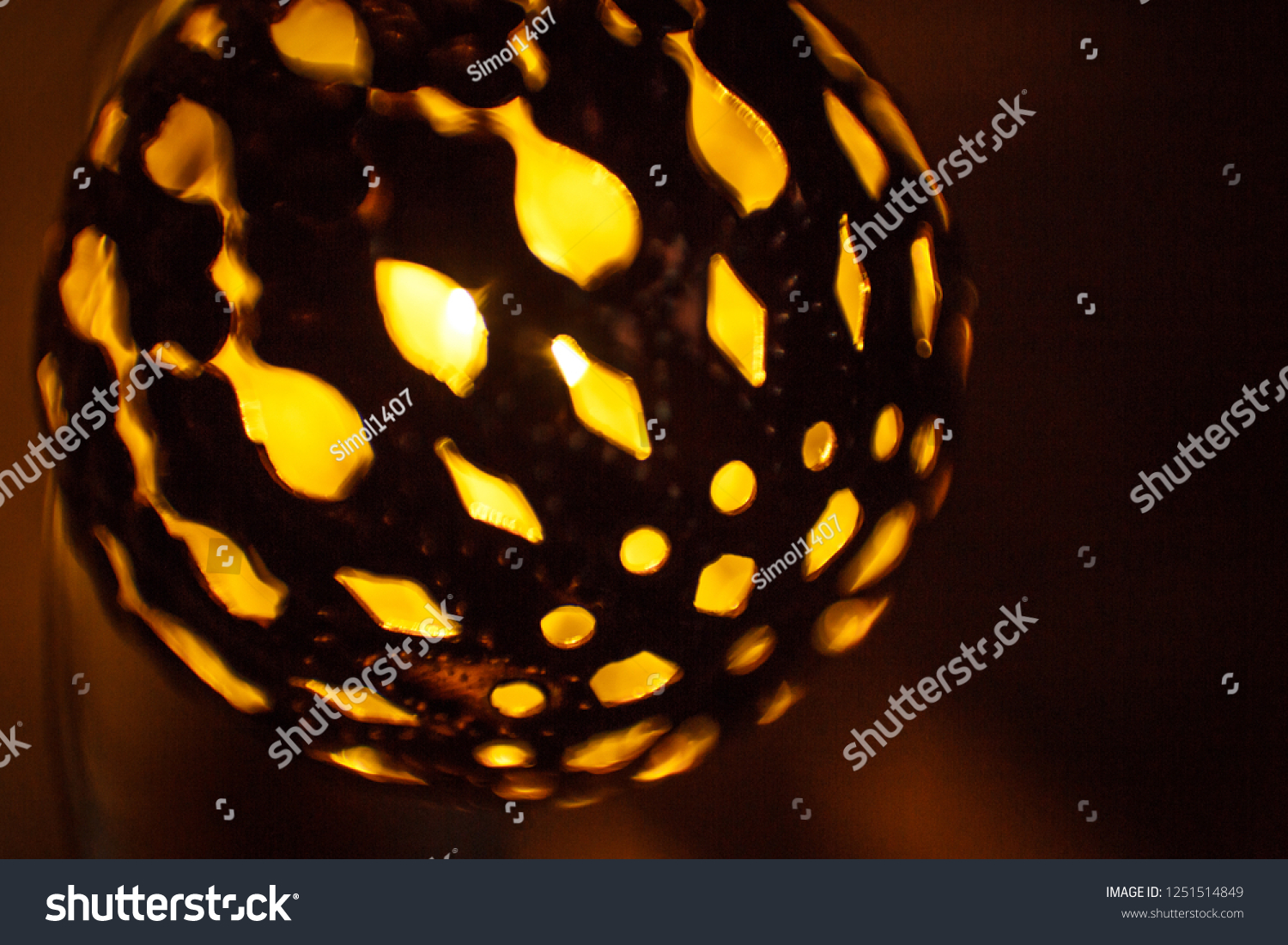 Festive garland carved metal bowl is lit from within with a Golden light. Bronze balls with slots-Christmas lights, creating a festive mood #1251514849