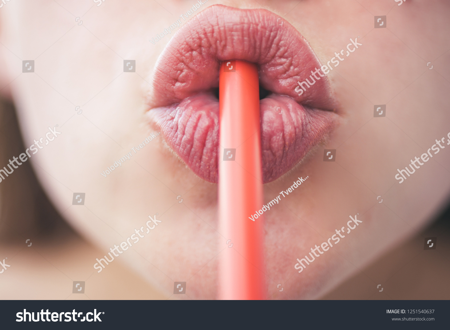 Drinking Straw Day. Sipping drink through straw. Female lips while drinking with straw. Drinking tube is a small pipe to consume a beverage. Orange plastic tube. Drinking straw in mouth. #1251540637