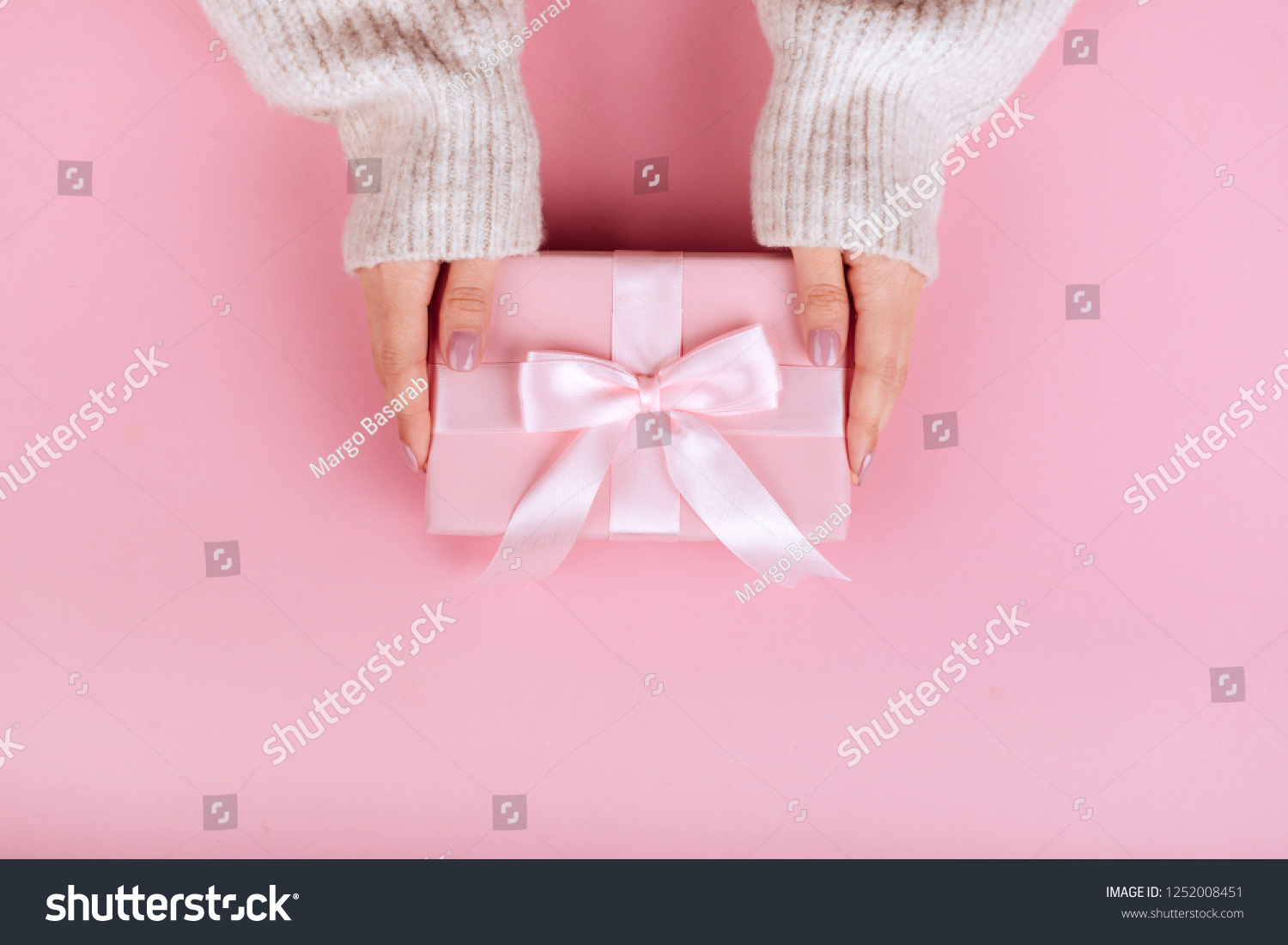 Female hands holding a small gift wrapped with pink ribbon. Selective focus,Selective focus #1252008451