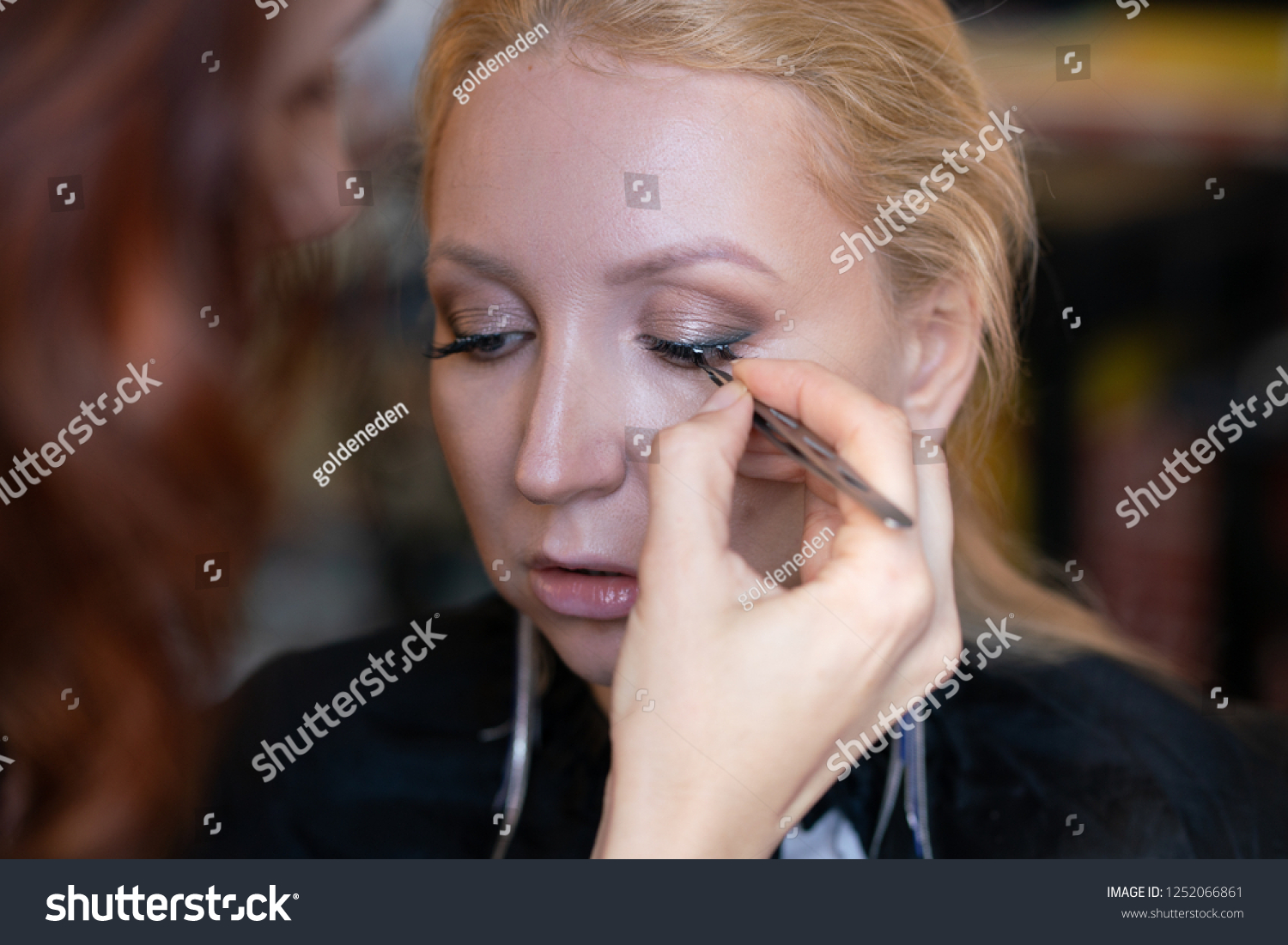 professional makeup artist applies makeup step by step on the face of a woman blonde #1252066861