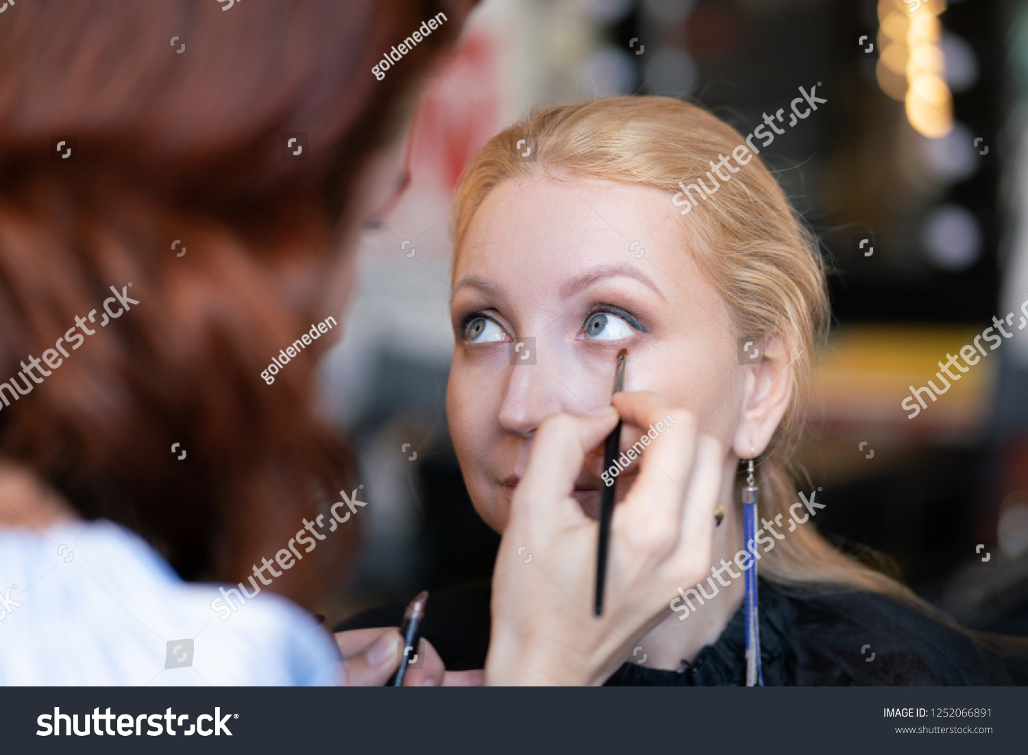 professional makeup artist applies makeup step by step on the face of a woman blonde #1252066891