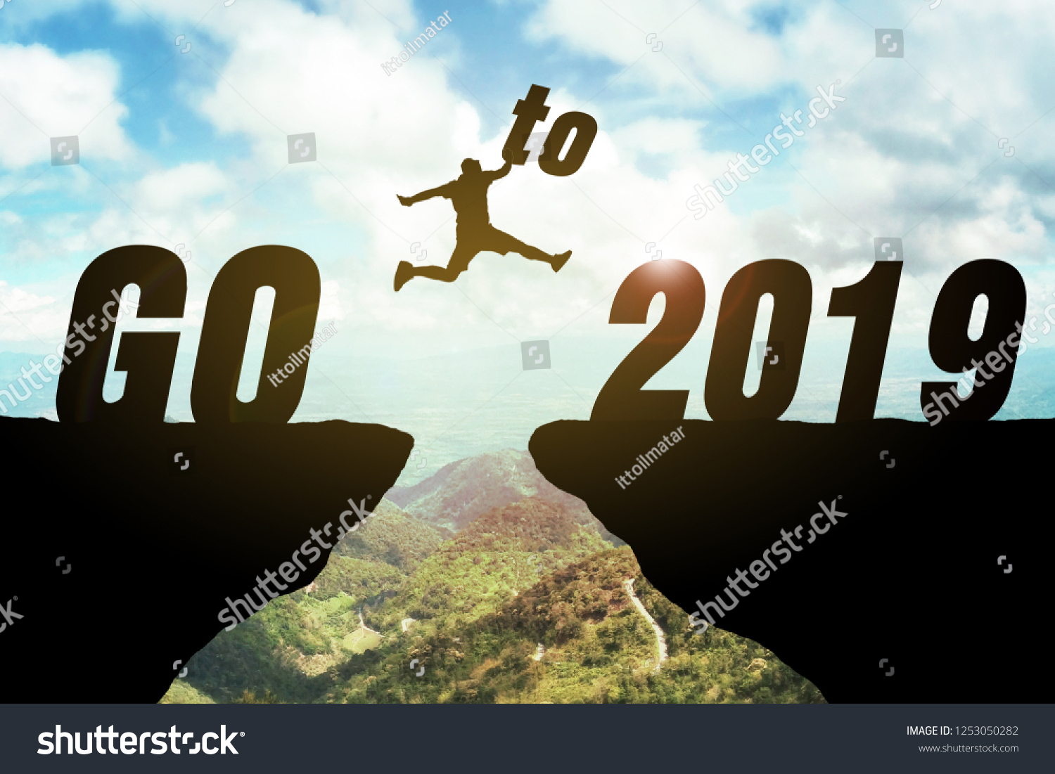 Silhouette of business man jump between cliff. keep go on to success concept at 2019 is coming over a beautiful high view mountain background. ready in 2019 years. GO TO 2019 YEAR CONCEPT #1253050282
