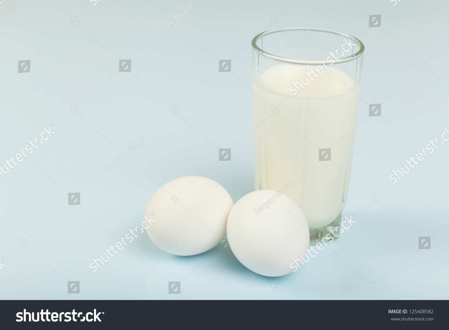 Milk in a glass jar and eggs on the table #125408582
