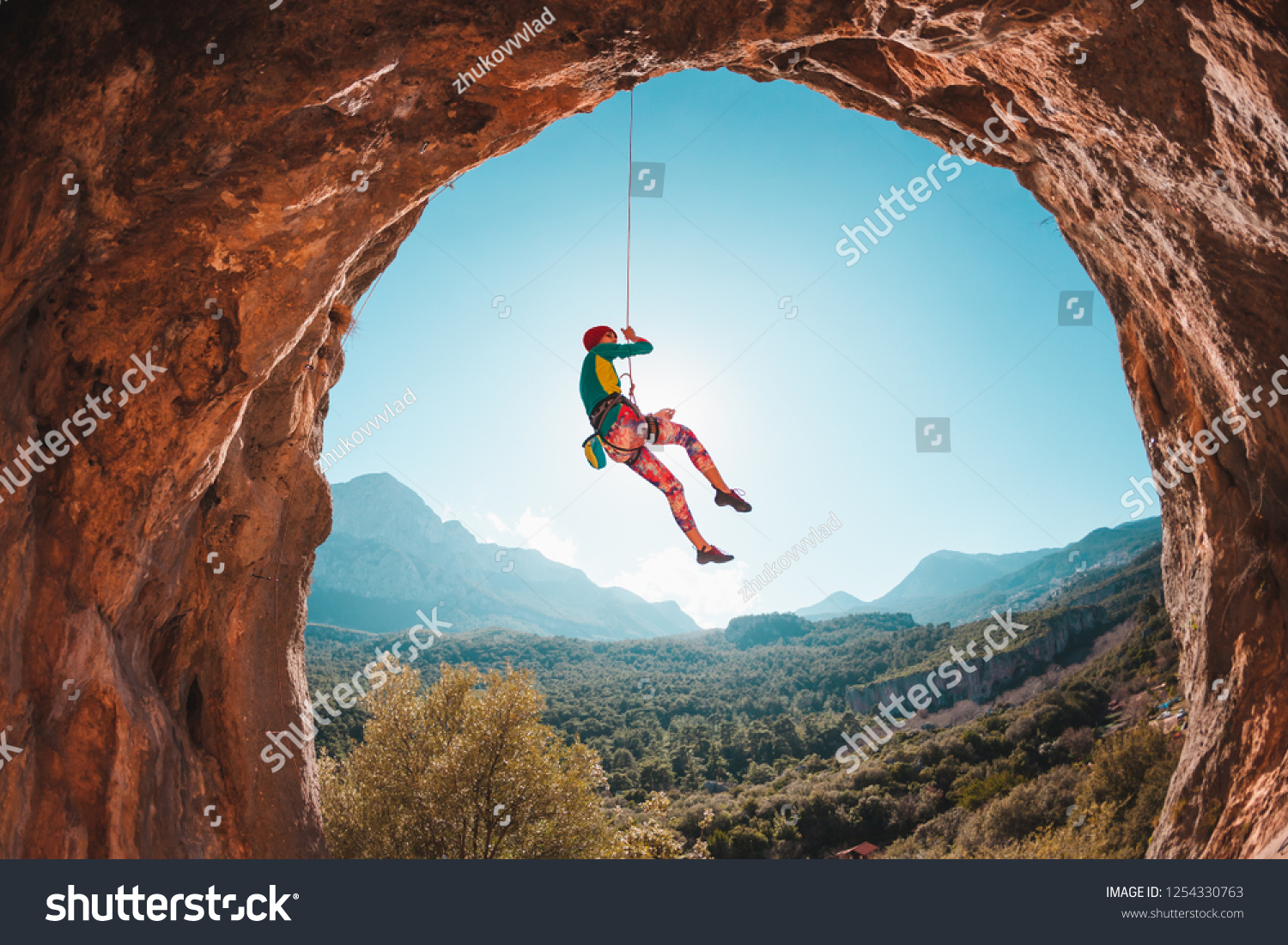 The climber is hanging on a rope. The girl goes down. Rock climbing in Turkey. Mountain landscape. A woman is engaged in extreme sports. Rock in the form of an arch. Climbing route in the cave. #1254330763