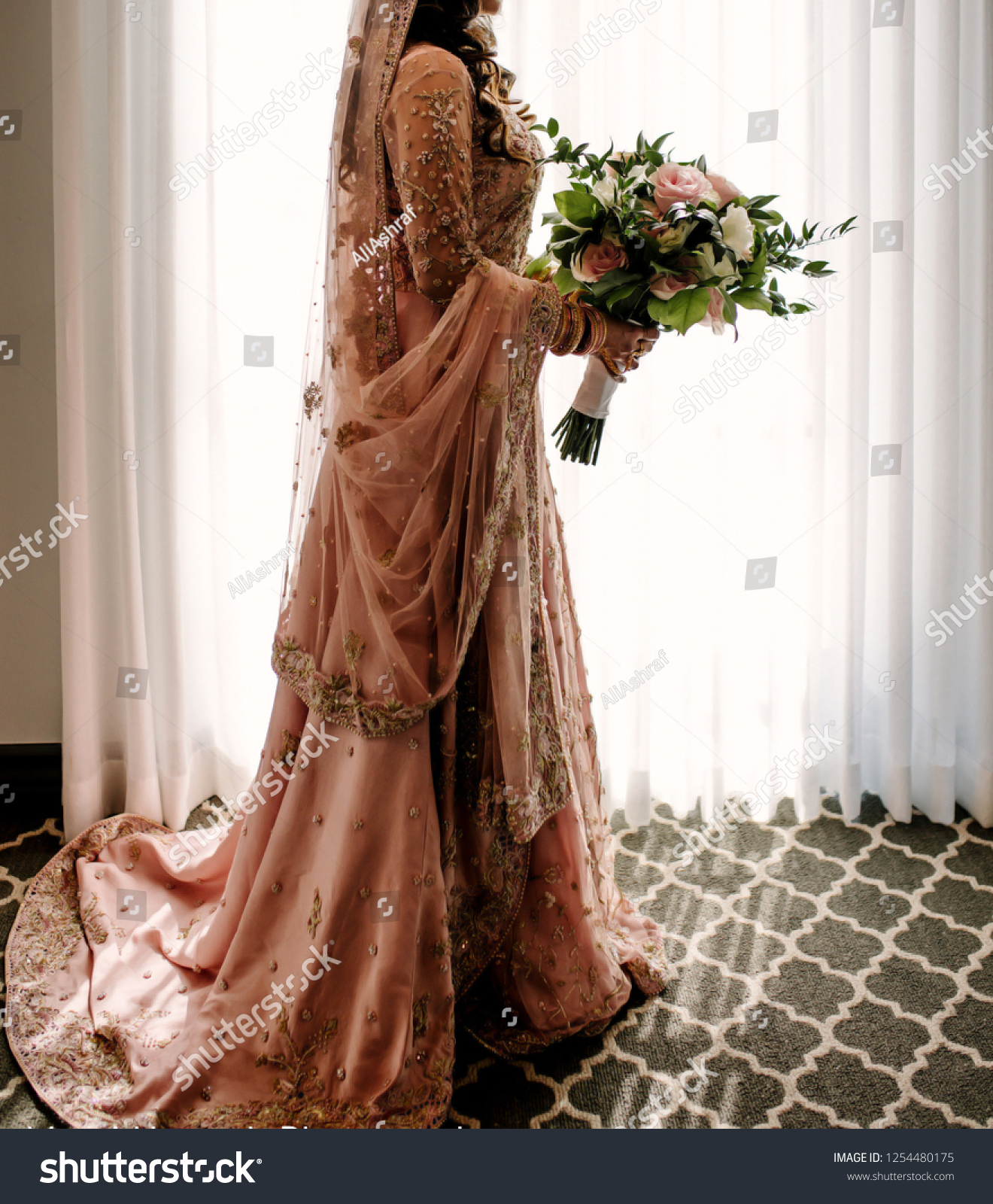Pakistani Indian bride holding the bouquet and wearing wedding Lehnga skirts dress #1254480175