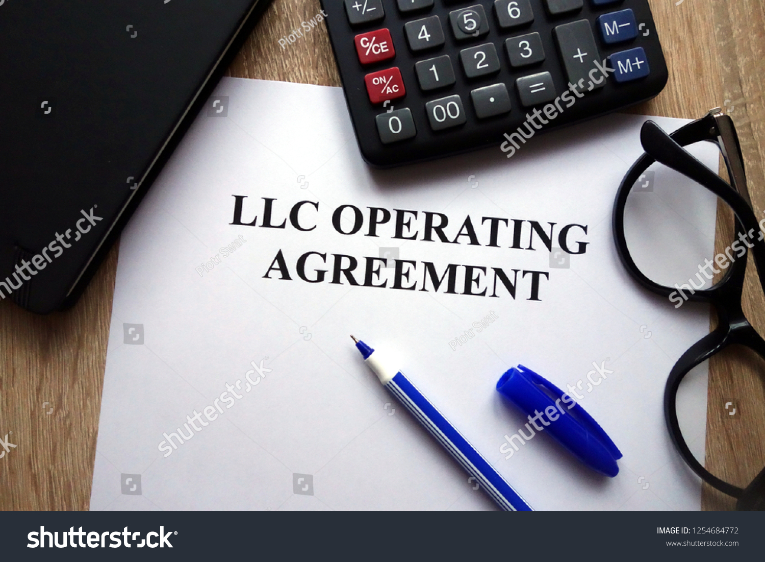 LLC operating agreement, pen, glasses and calculator on desk #1254684772
