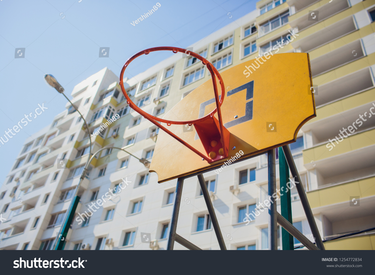 Basketball hoop with backboard in residential district for street basketball game, outdoors sports and recreation. #1254772834