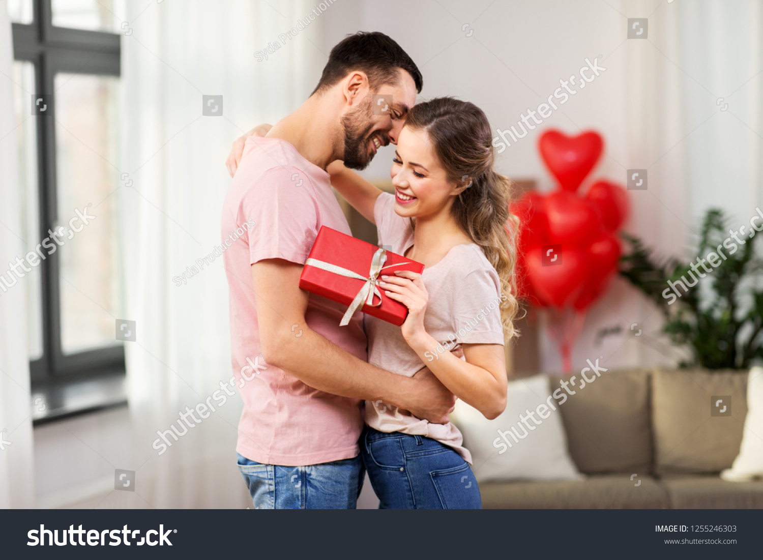 valentines day, relationships and people concept - happy couple with gift box hugging at home #1255246303