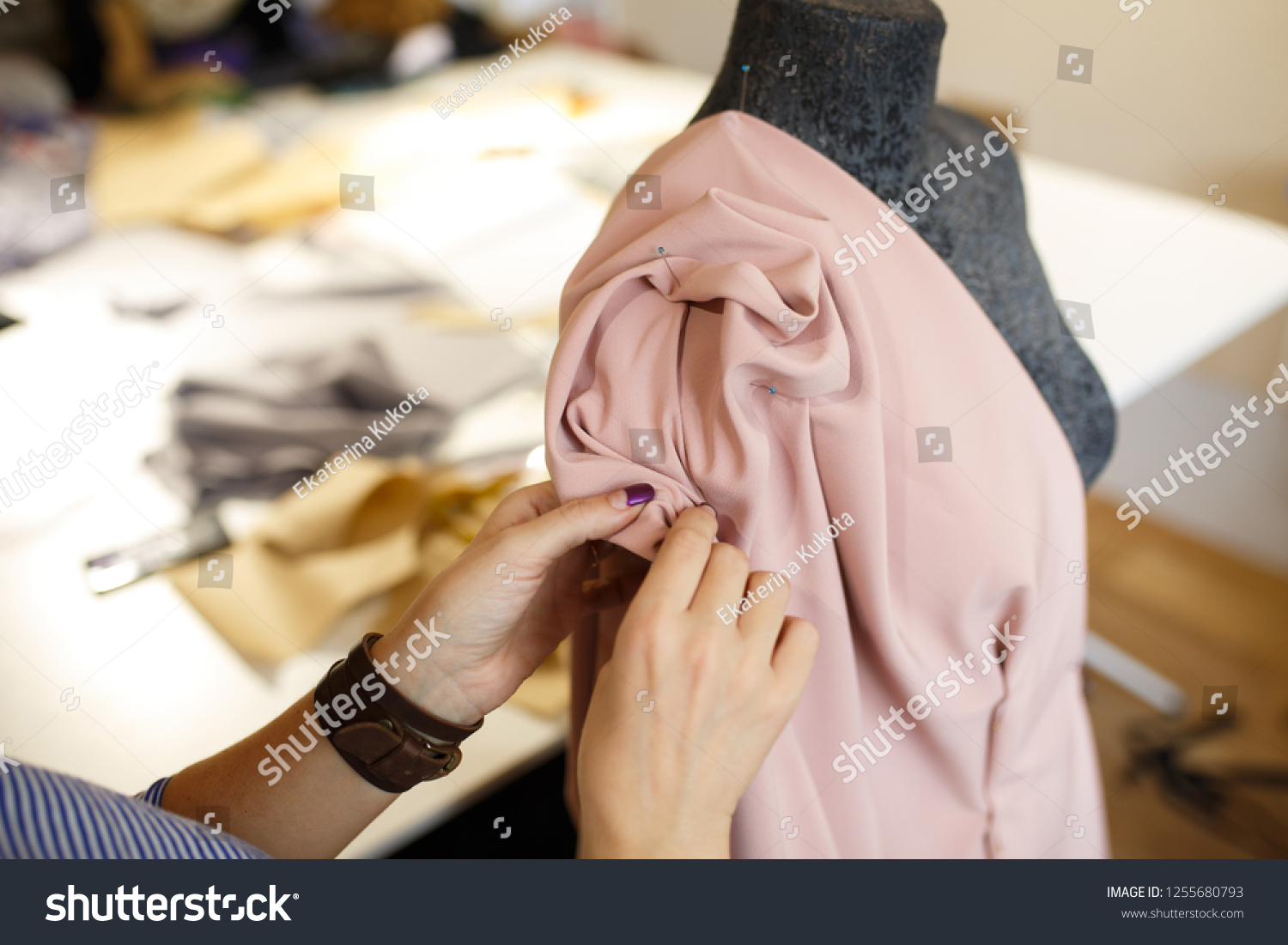 female dressmaker attach fabric to mannequin with needles. creating dress design. Tailor industry concept. #1255680793