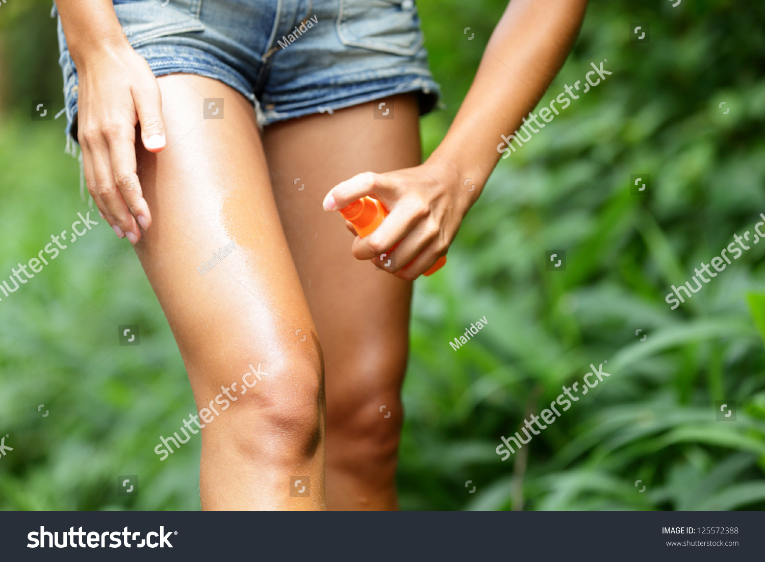 Mosquito repellent. Bug spray anti insects for zika virus in rain forest jungle. Woman spraying insect repellent putting on skin outdoor in nature using spray bottle. #125572388