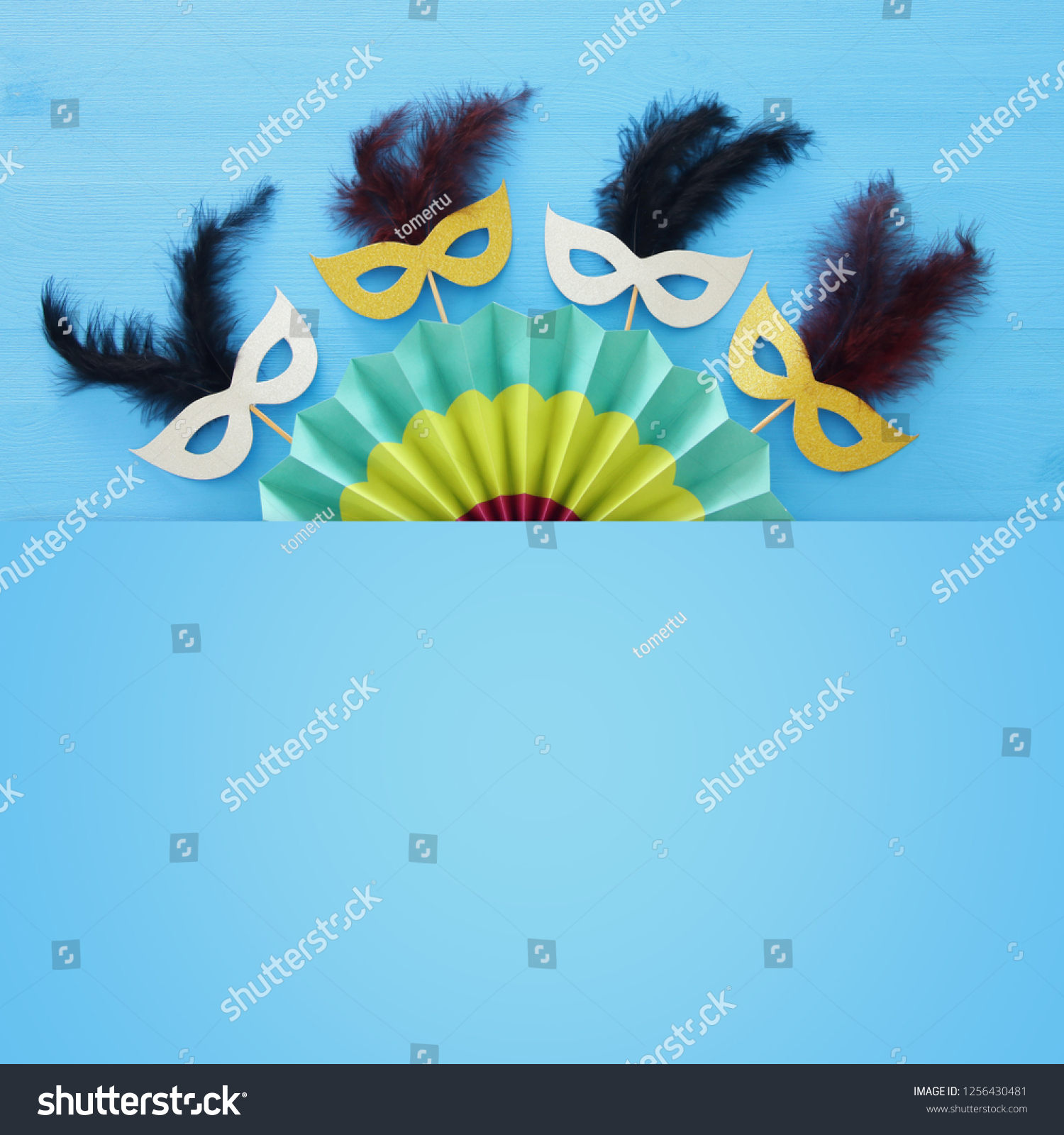 carnival party celebration concept with masks and colorful fan over blue wooden background. Top view #1256430481