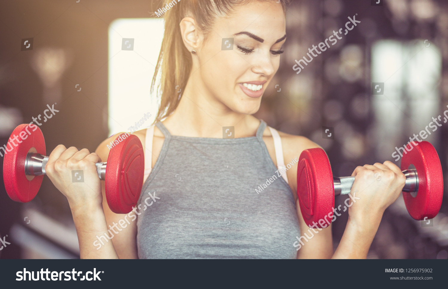 I am strong woman. Sportswoman working exercise for hands with weight. Close up. #1256975902