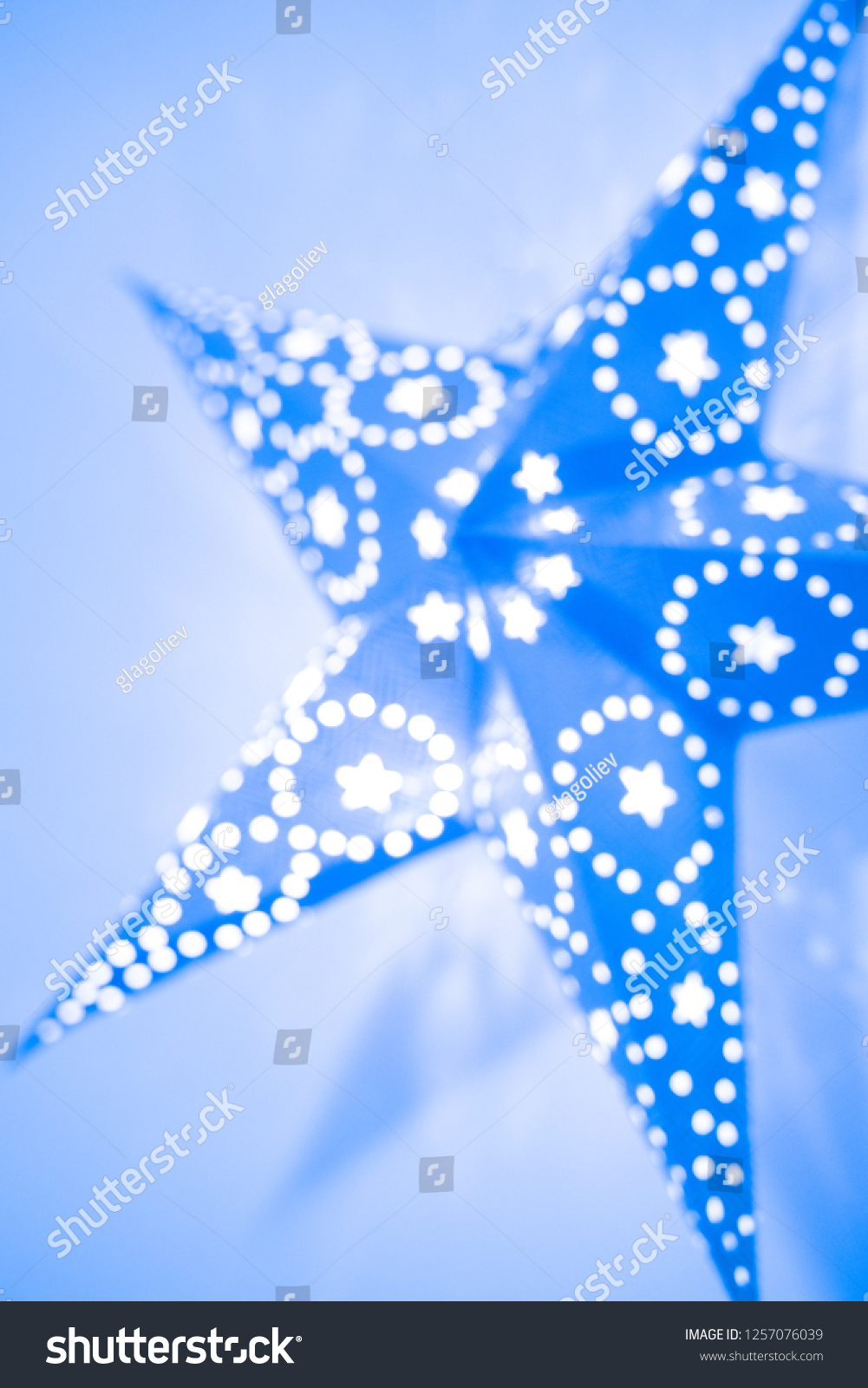 Christmas blur background with decorative star.  Decorative star with lamps on blue background. #1257076039