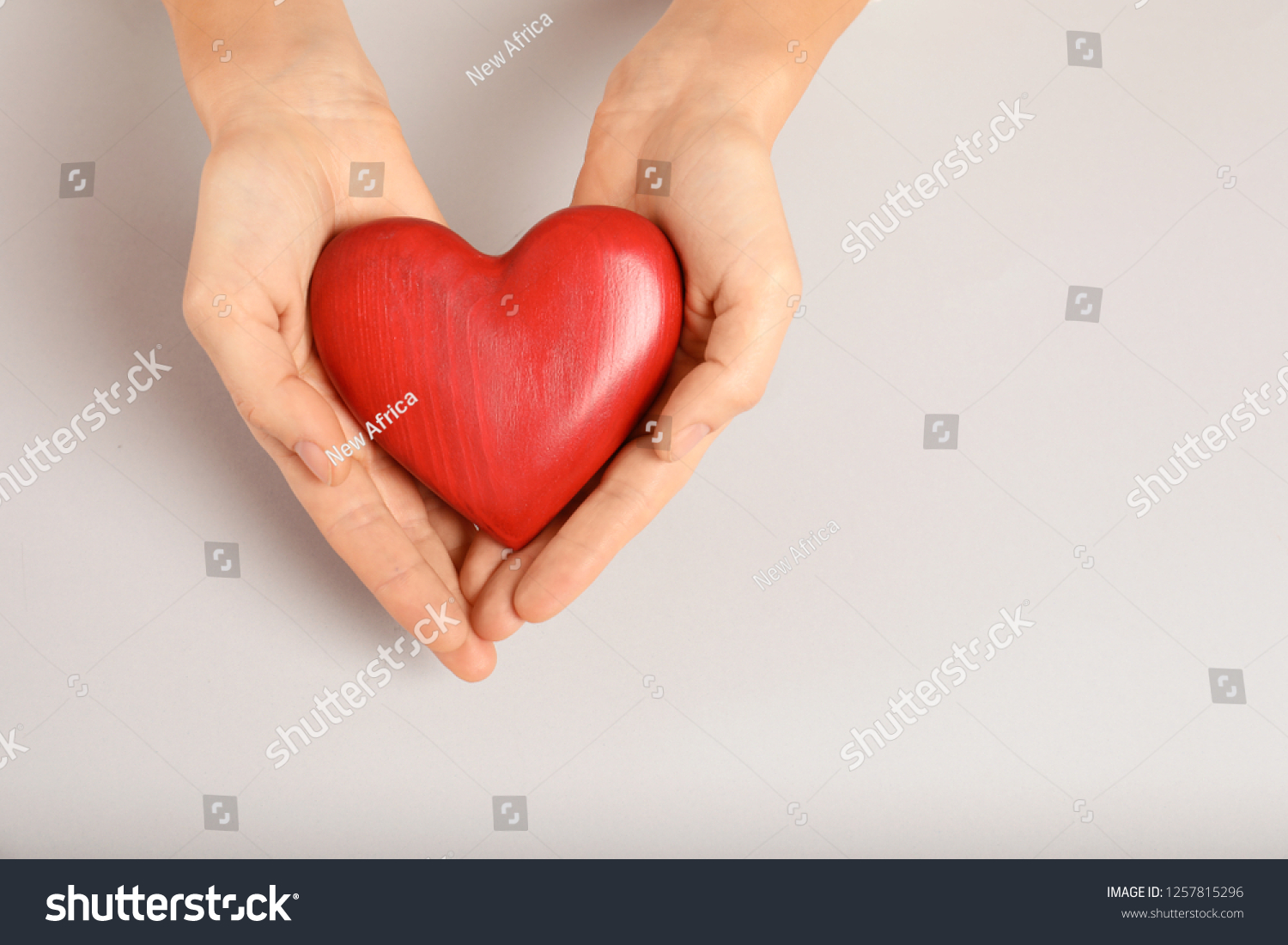 Woman holding decorative heart on light background, top view with space for text #1257815296