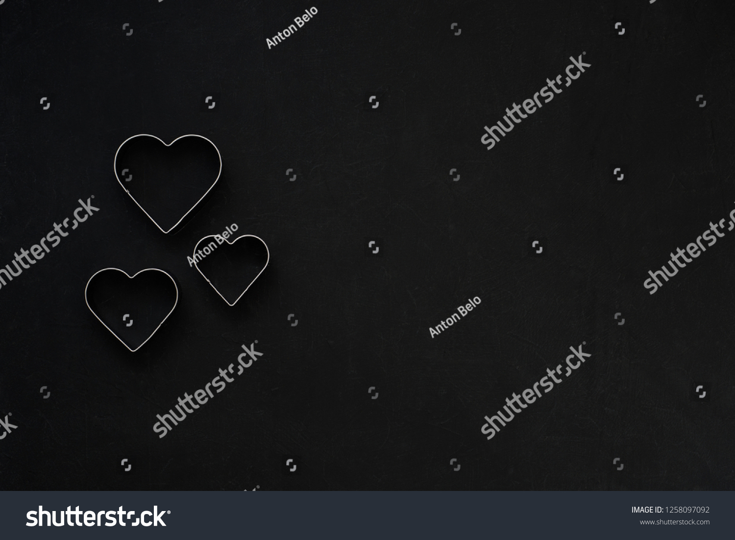 Metal hearts on a festive black background. Baking molds. Cookie cutters. Flat lay, top view #1258097092