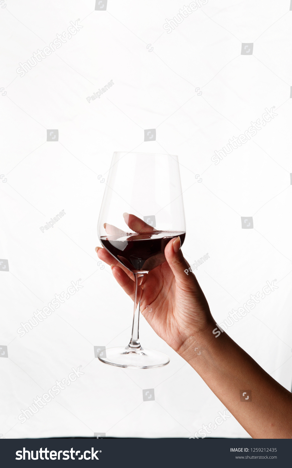 wine glass with red wine in hand on white background #1259212435