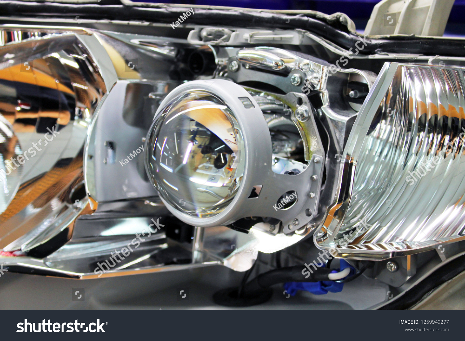 Macro view of repairing, installation and turning headlight of modern automobile and car projector lens. Vehicle head xenon lamp in details. Concept of auto detailing, light and LED technology #1259949277