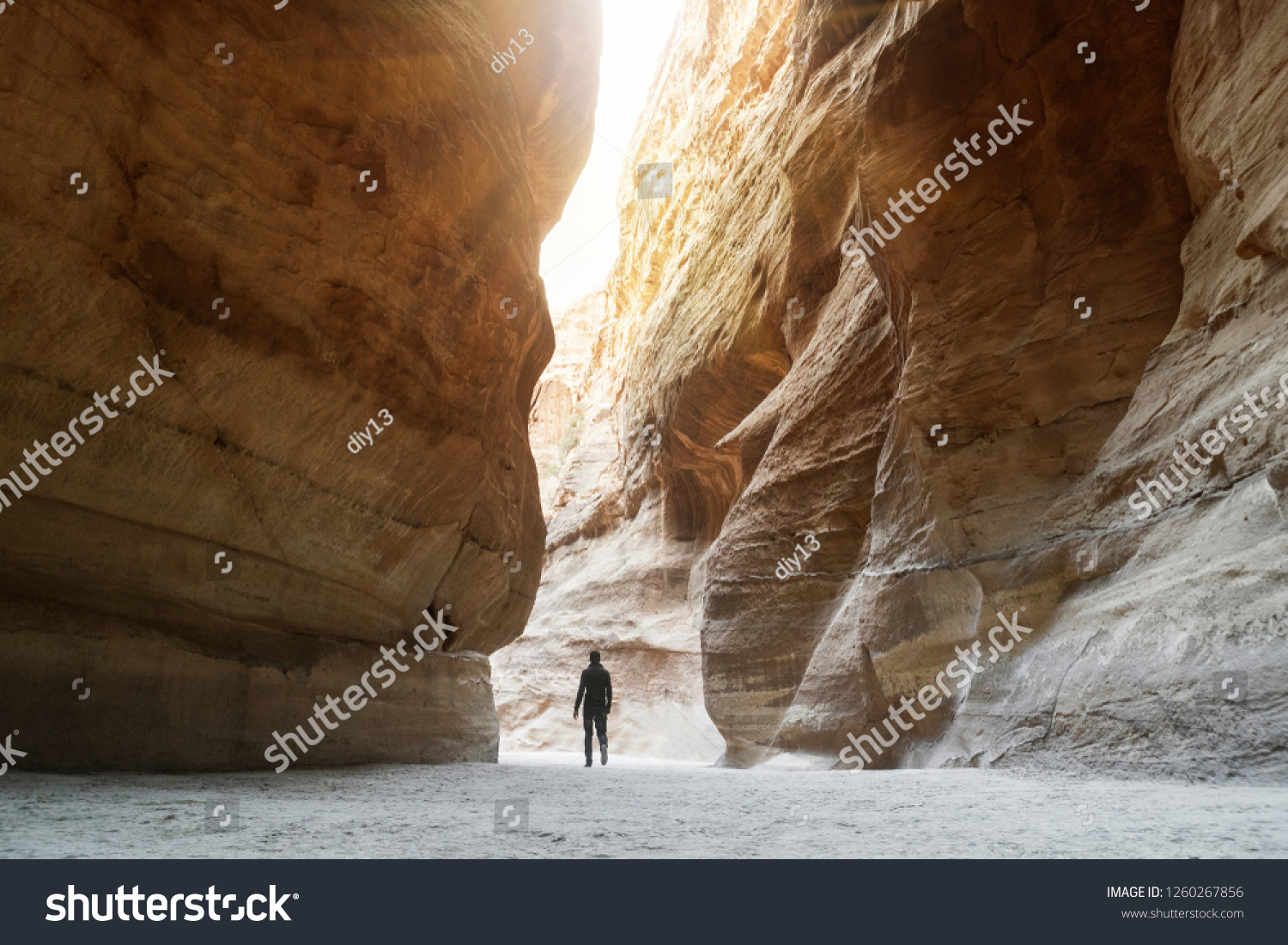 Tourist in narrow passage of rocks of Petra canyon in Jordan. UNESCO World Heritage Site. Way through Siq gorge to stone city Petra. lonely man walking among the rocks. sunlight breaks through rocks. #1260267856