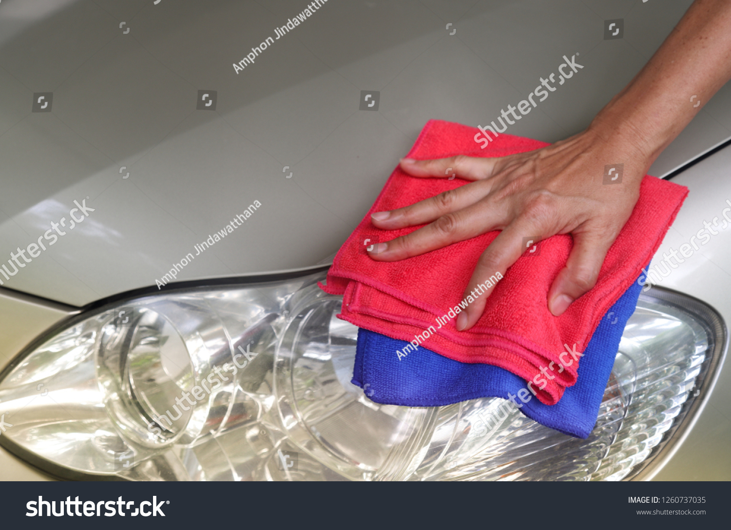 Closeup of car cleaning  with pink and blue microfiber cloths by woman owner's hand in sunny day. The lovely family activity. #1260737035