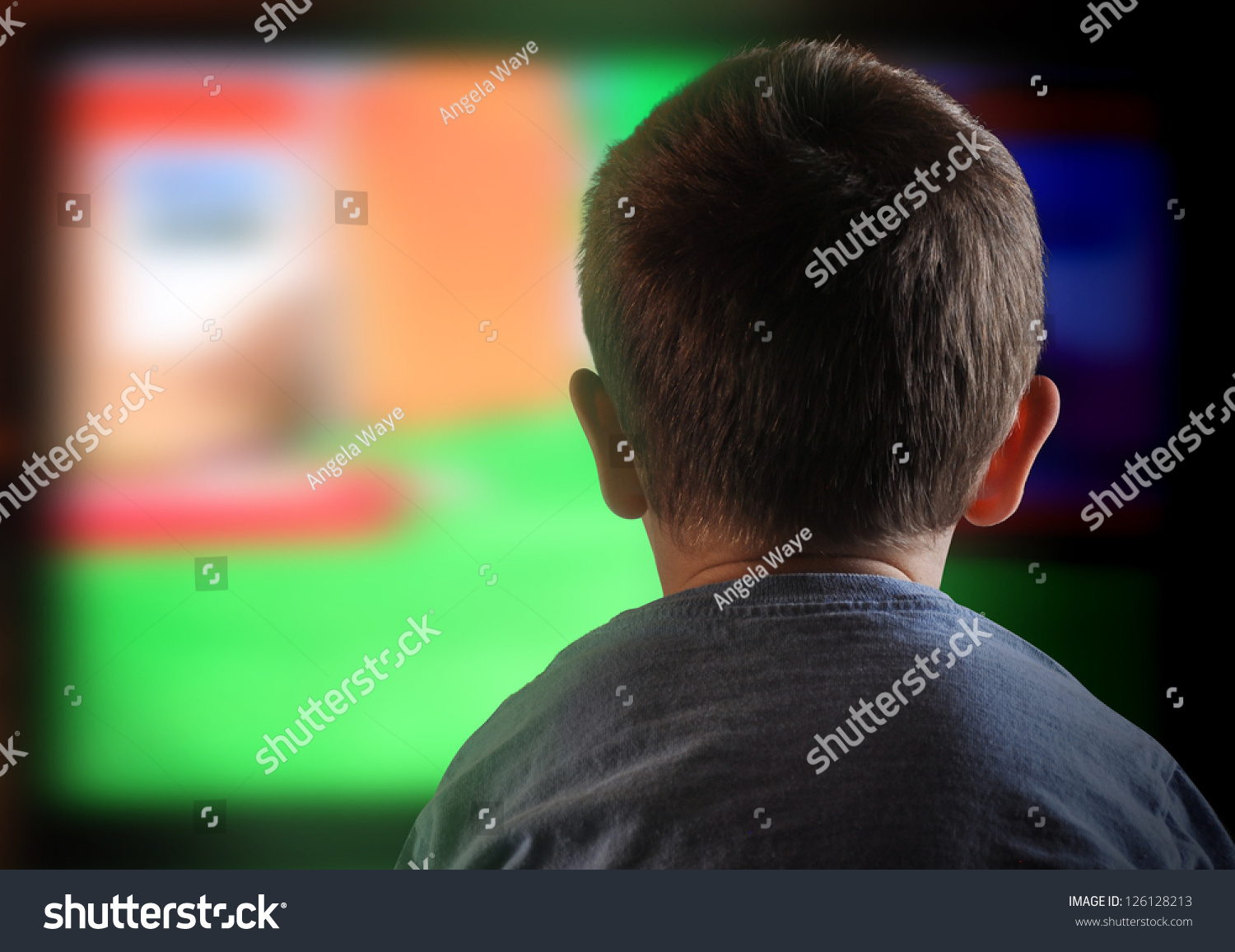 A young boy is watching a television screen with his back for a tv effect on children or a communication concept. #126128213