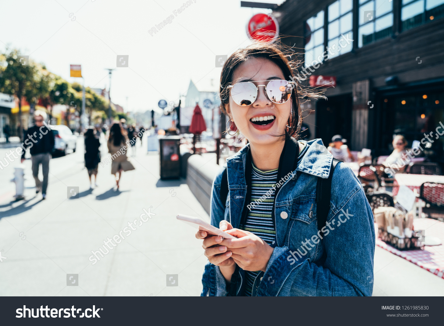Asian woman standing on old port street using cellphone waiting for friends in front the restaurant outdoors cheerfully smiling. young girl searching direction to hotel in busy urban san francisco. #1261985830