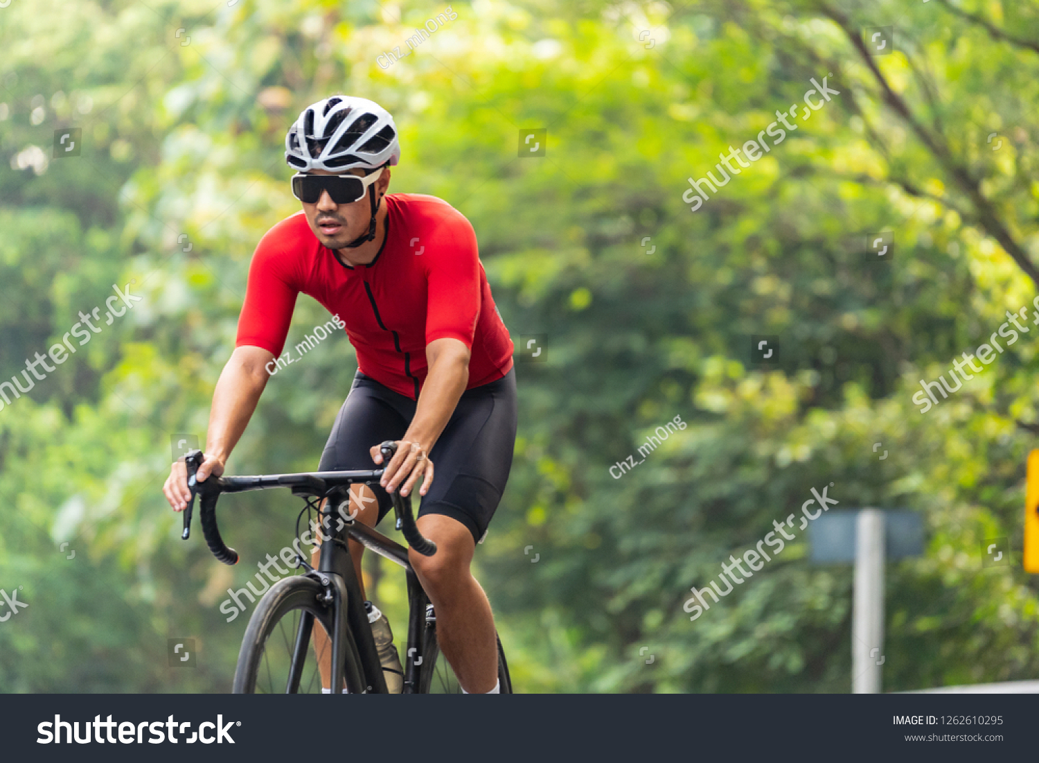 Asian man in red cycling jersey, white helmet and sun-glasses, riding on road bike on his way in the morning. exercise routine for good healthy. #1262610295
