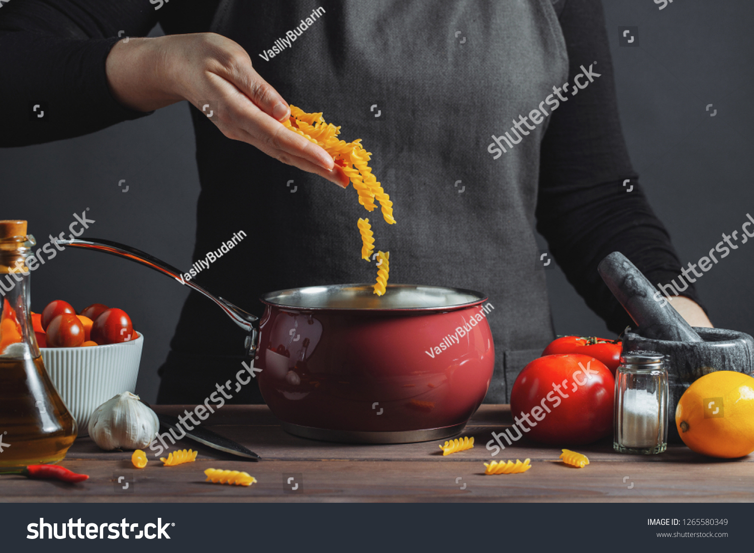 Cooking italian pasta in a pot in the kitchen, Chef preparing food, meal. The woman-the cook throws into the pot the pasta fusilli #1265580349
