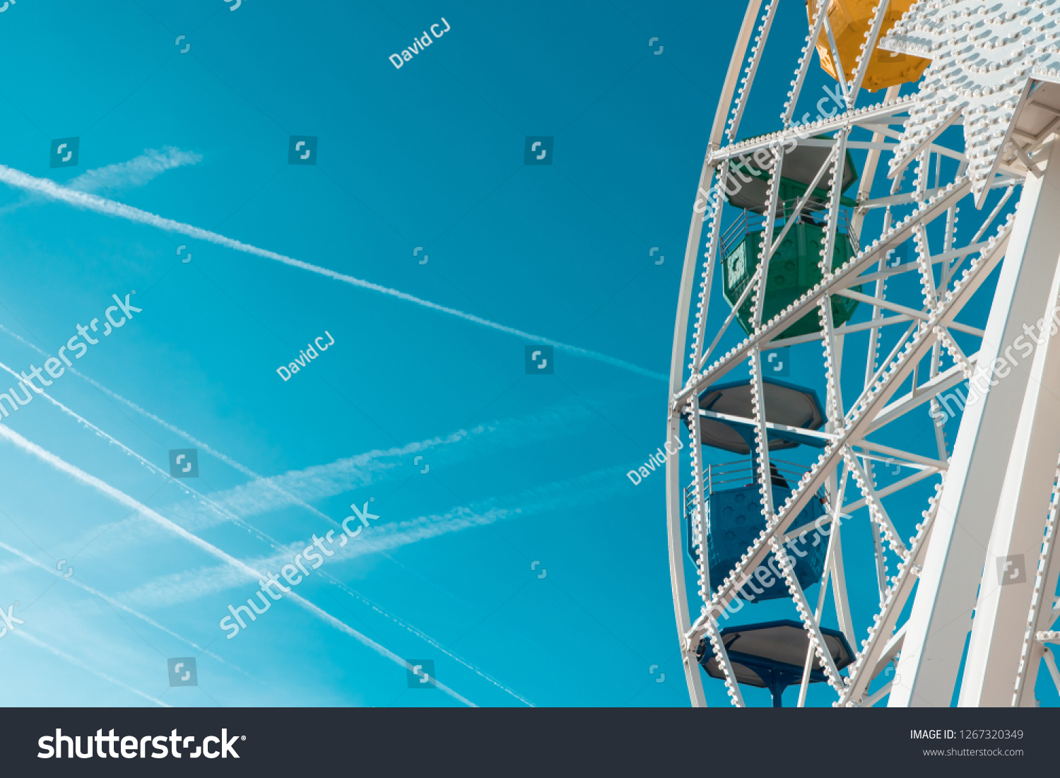 Colorful ferris wheel at fun amusement park with clear blue skies. #1267320349