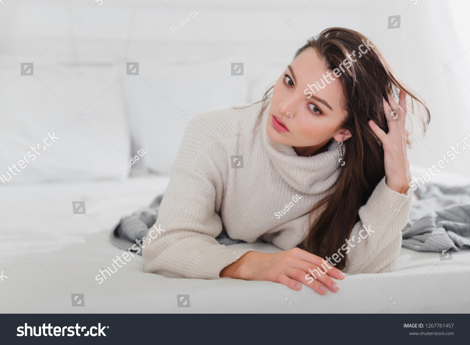 Girl brunette sweater pants gray lies on her hand. Concept thinks, choice, solution, dilemma, skin care, self care, sleep. Copy space left. Closeup. #1267761457