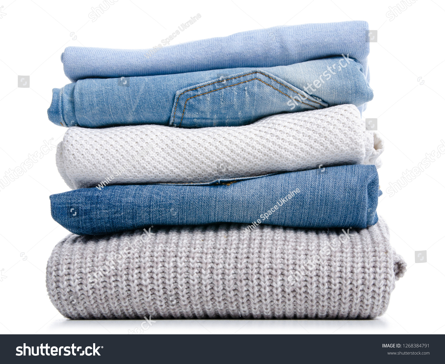 Stack of clothing jeans sweaters on a white background isolation #1268384791