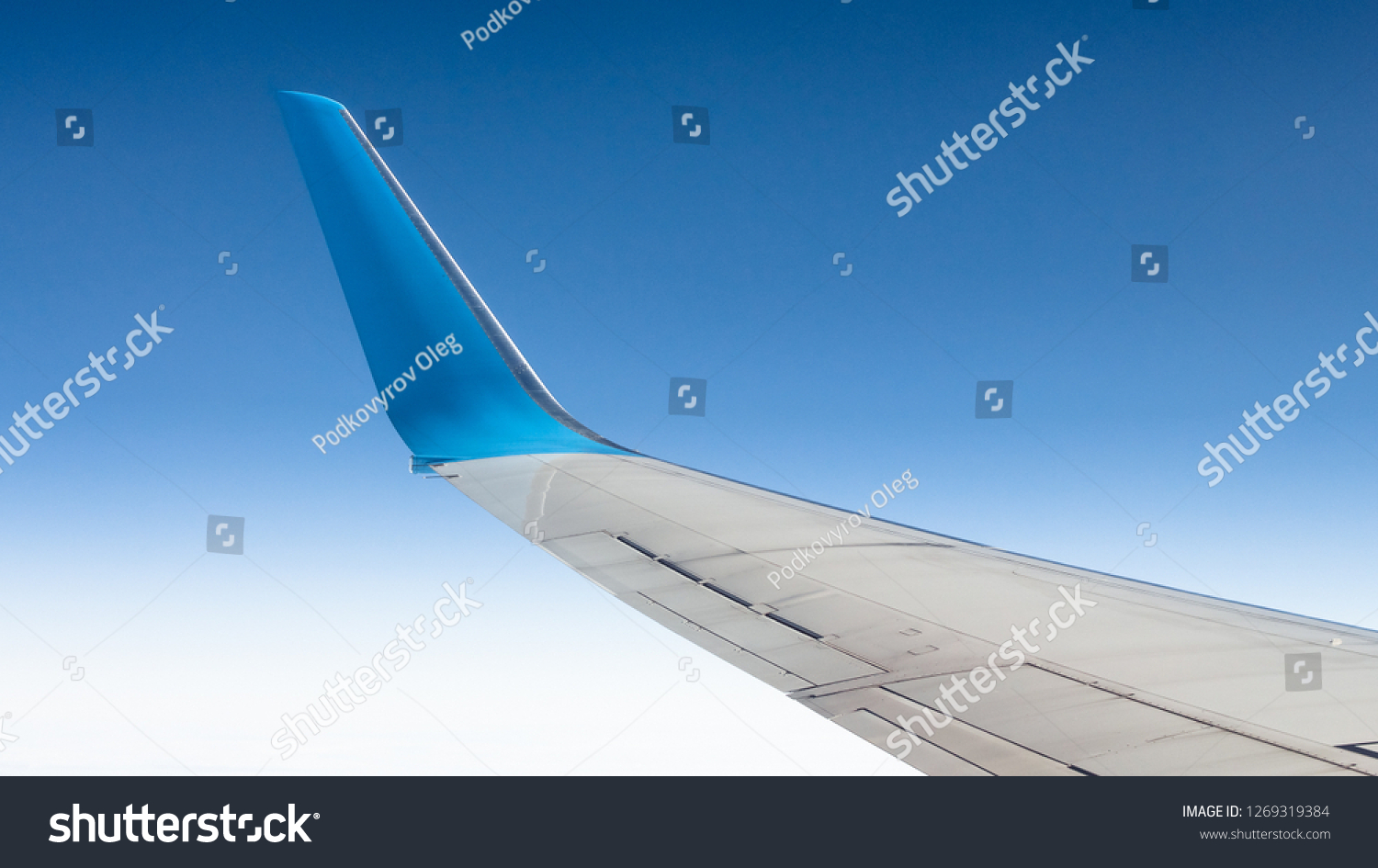View from the window to the winglets of the civilian aircraft. Blue cloudless sky #1269319384