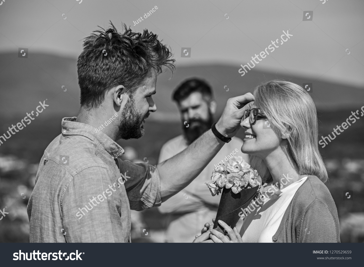 Couple in love dating while jealous husband fixedly watching on background. Unrequited love concept. Lovers meeting outdoor flirt romance relations. Couple romantic date lover present bouquet flowers. #1270529659