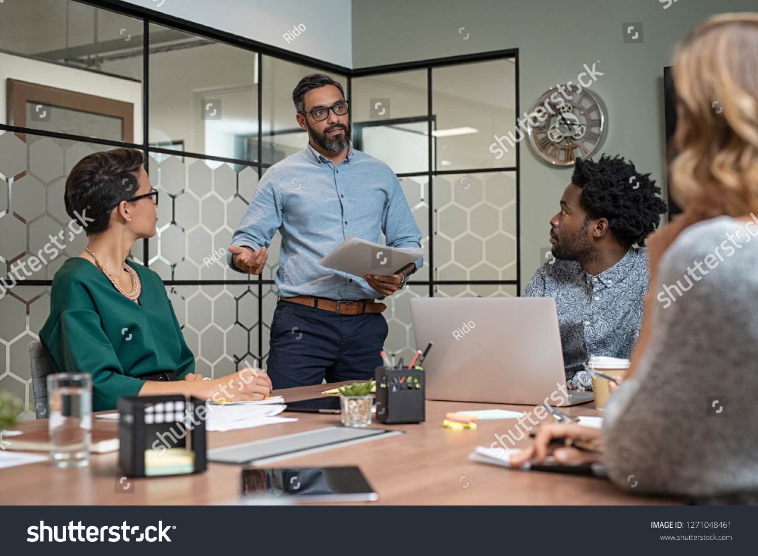 Confident mature businessman giving a presentation to his team in office. Business brief with annual goals with employees and mature boss in meeting room. Multiethnic leader training business people. #1271048461
