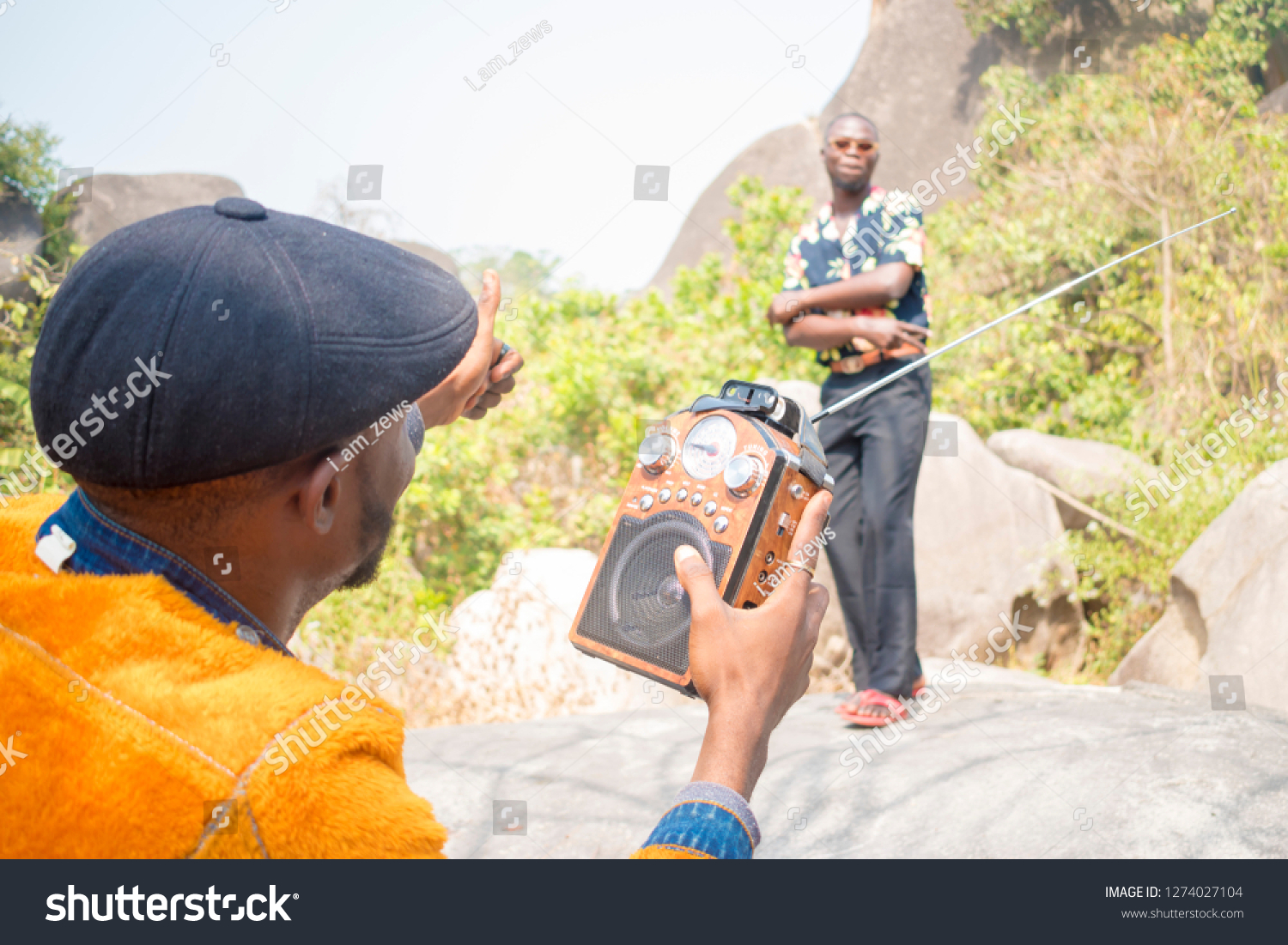 young young black man holding a radio giving thumbs up to a friend who's dancing  #1274027104