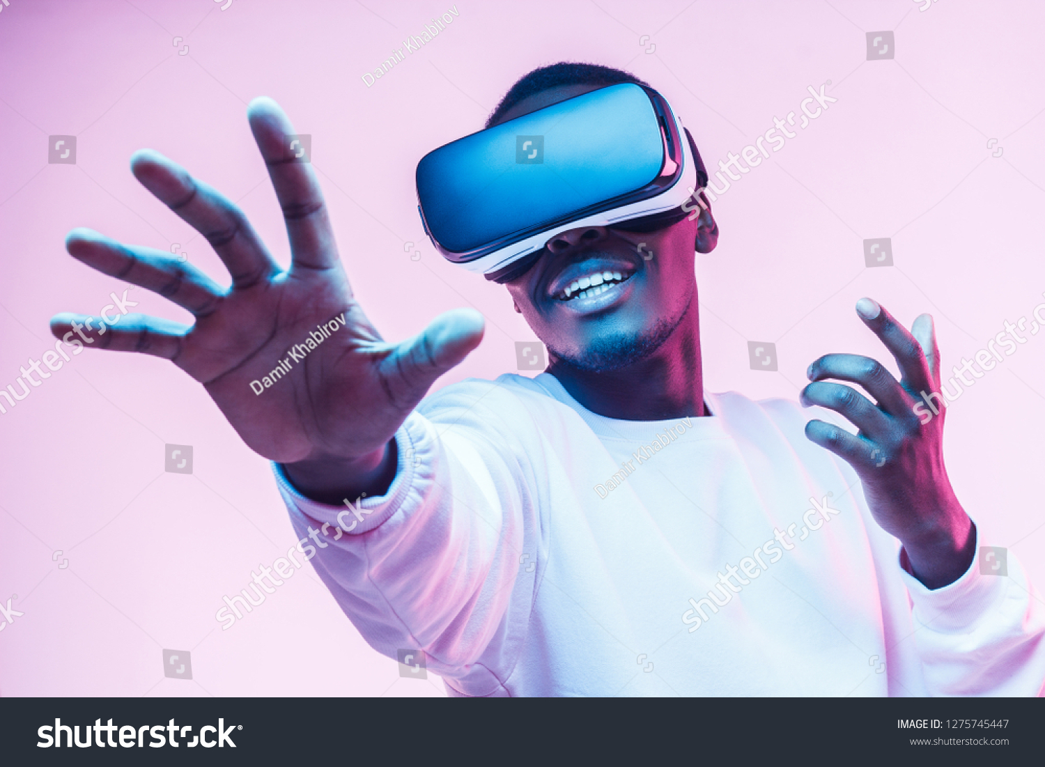 African american man in vr glasses, playing video games with virtual reality headset, trying to touch something with hand #1275745447