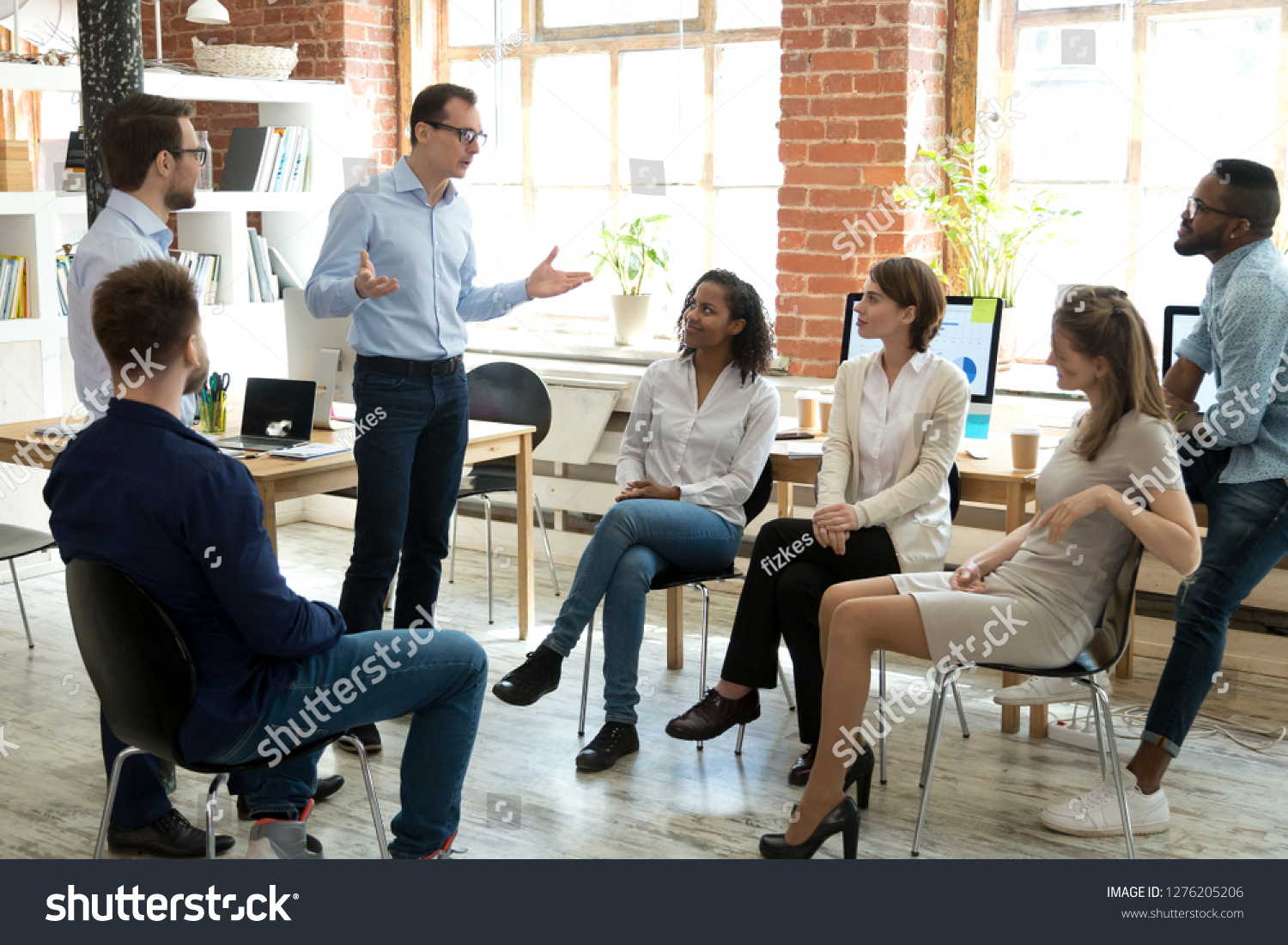 Diverse business team employees listening to male manager coach speaking at group office meeting, mentor executive leader talking during briefing, multi-ethnic workers engaged in corporate training #1276205206