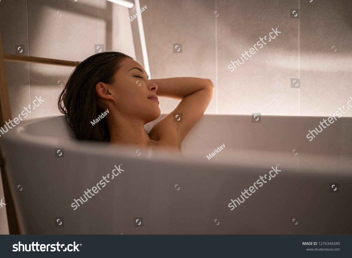 Luxury bath woman relaxing in hotel spa bathtub or home bathroom for total relaxation. Asian lady taking a bath sleeping in warm water, winter wellness. #1276344340