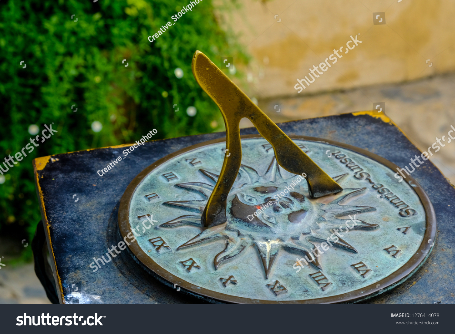 Close-up of a brass sundial mounted on a stone plinth in a garden, Sundial in the Summer sun. #1276414078