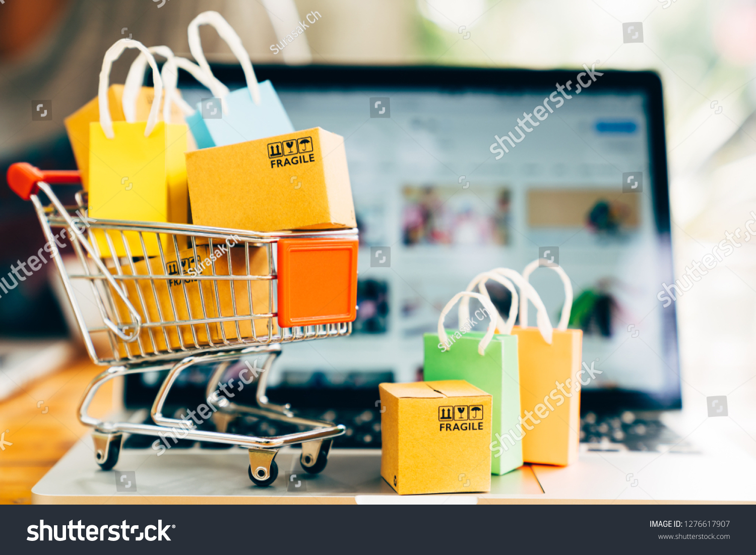 Product package boxes and shopping bag in cart with laptop computer which web store shop on screen for online shopping and delivery concept #1276617907