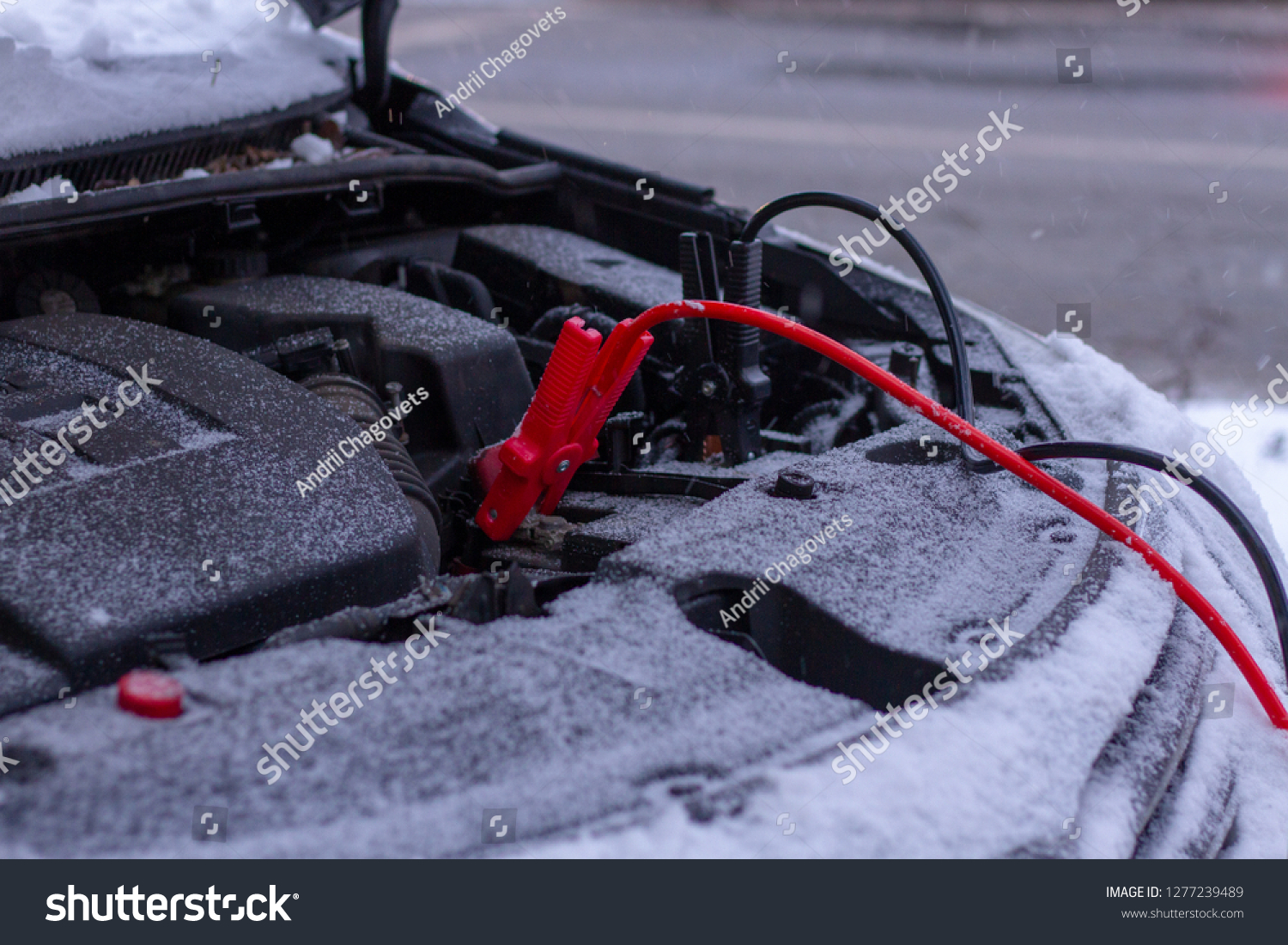 Quickly charge the car battery with jumper cables and another car. Open car hood with battery wires in snowy weather. Jump-Starting the Dead Battery. #1277239489