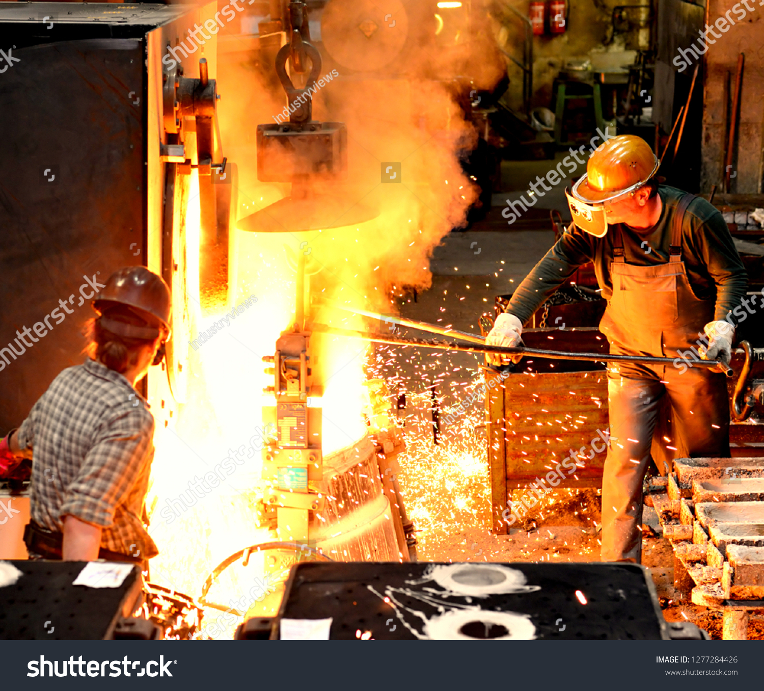 workers in a foundry casting a metal workpiece - safety at work and teamwork  #1277284426