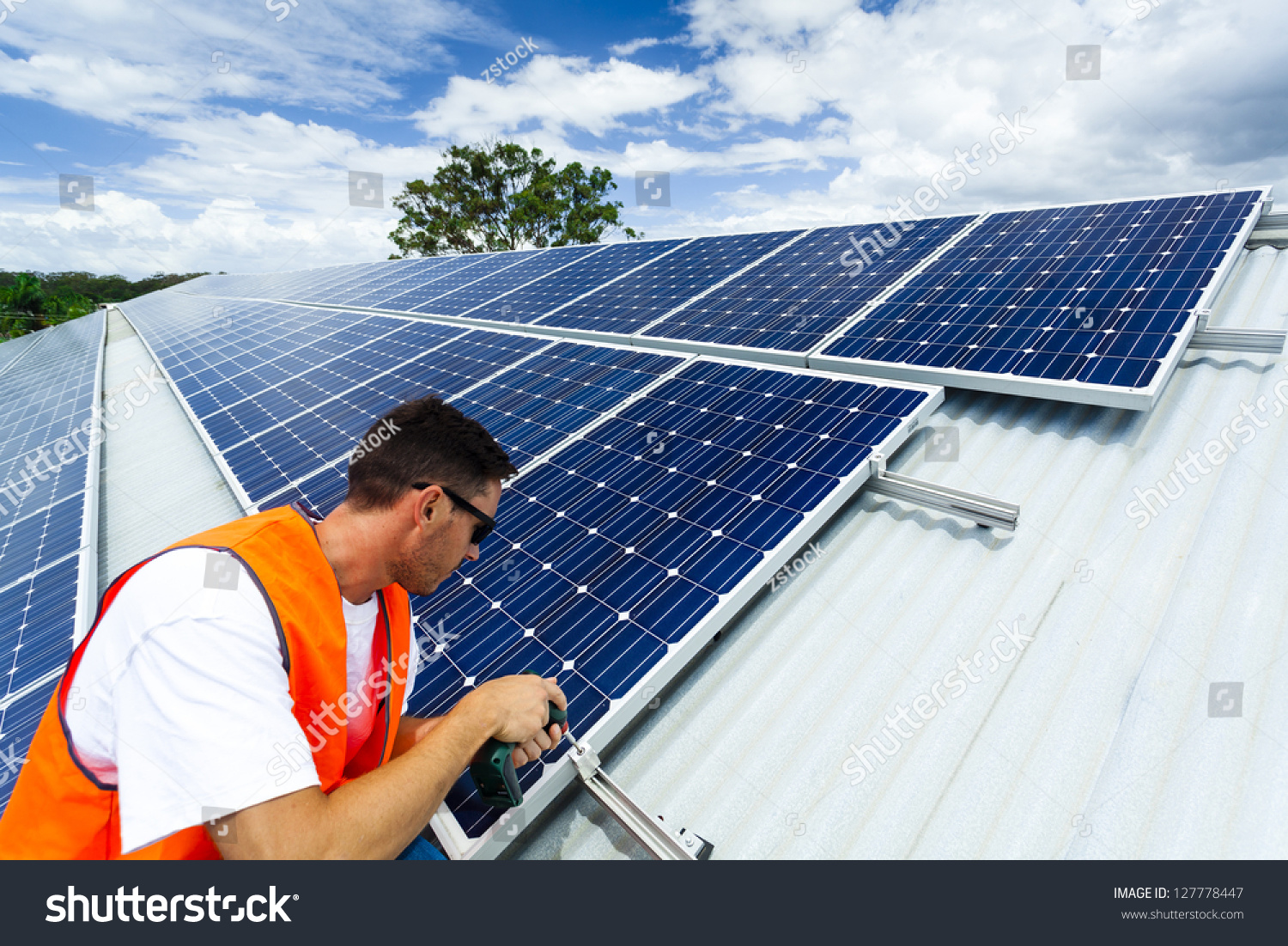 Young technician installing solar panels on factory roof #127778447